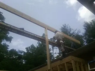 Carpenter setting a ridge beam over a new addition frame — Ice Dam Removal by Roofing Brothers in Orange City