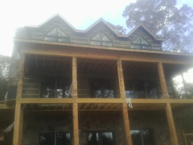 Dormers and porch framing on a large log home under construction — Roof Coating work by our crew in Orange City