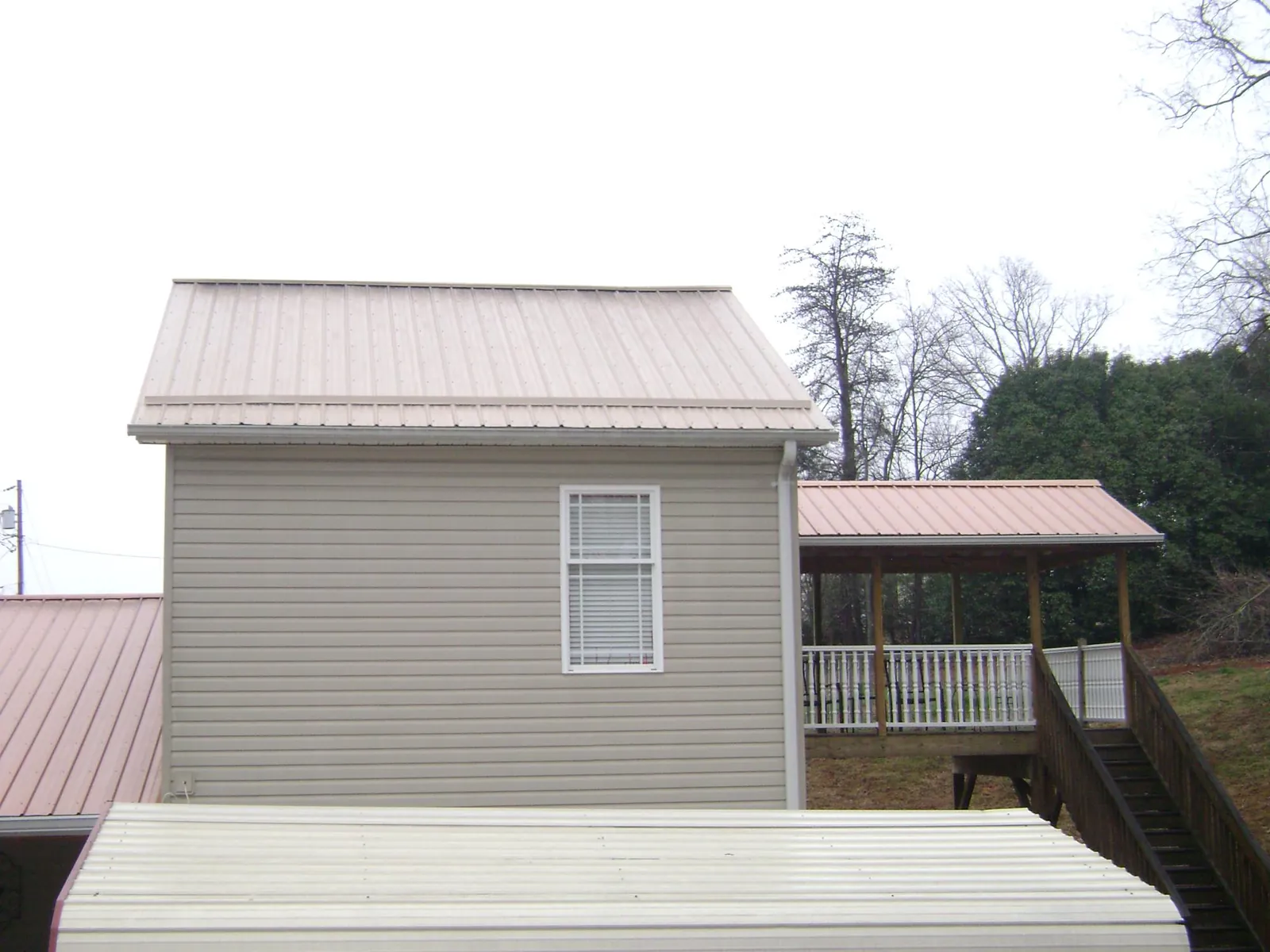 Tan metal roofs on a two story addition and attached porch, from a Roof Replacement job in Orange City